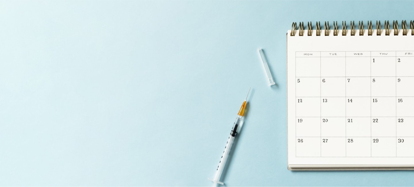 Vaccine shot and calendar on a table