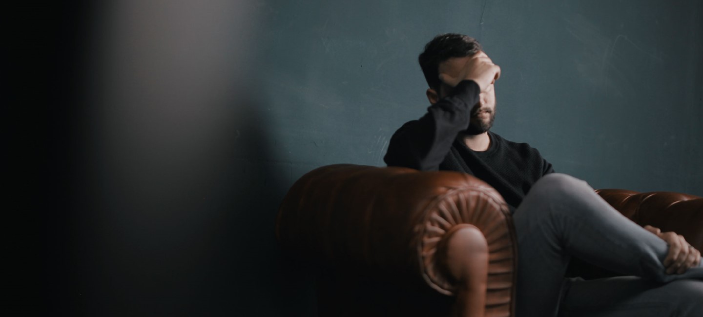 Cognitive-dysfunction-in-migraine_2320x1000px.jpg Person sitting on an armchair, touching his head.