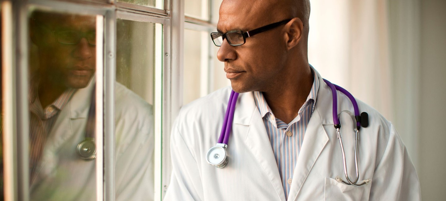 DailyChallengesWithMigraine2320x1000.jpg HCP looking out of a window with a pensive look on his face